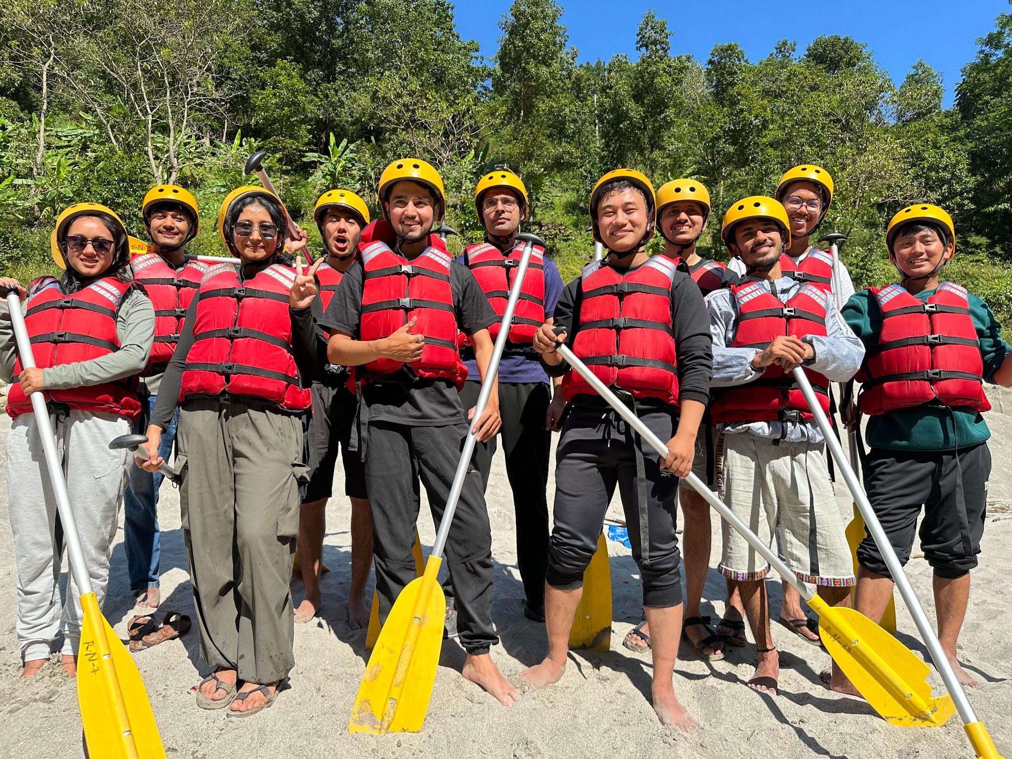 Team geared up with life jackets, helmets, and paddles